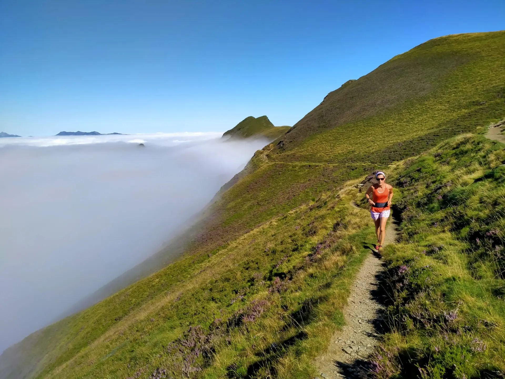 Traileuse courant sur un sentier de montagne avec la mer de nuage à Hautacam