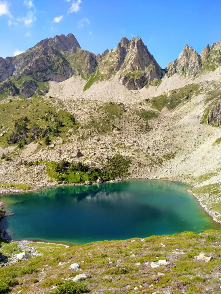 Lac aux eaux turquoises avec des sommets acérés en fond et un ciel bleu