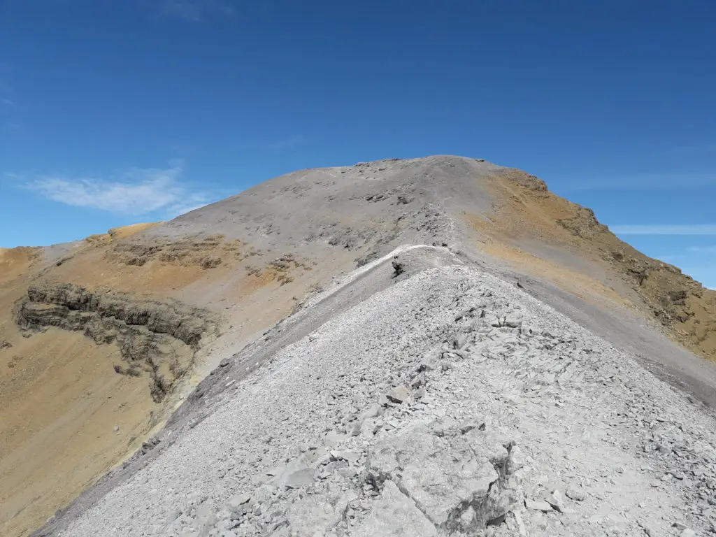 Arrivée sur le sommet minéral du Taillon, roche bicolore, grise de calcaire et orangée de grès. Ciel bleu à l'horizon