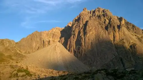 Sommet rocheux et abrupt éclairé par le soleil avec un pierrier en dessous