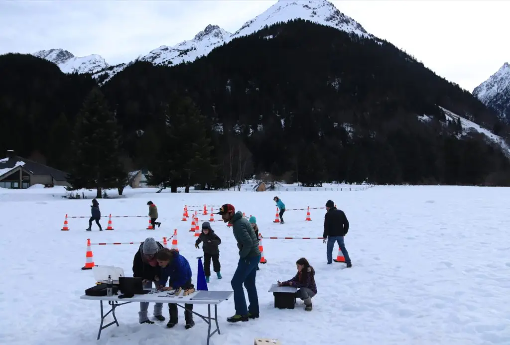 Famille jouant au jeu d'orientation Learn-O en hiver dans la neige à côté du Lac d'Estaing