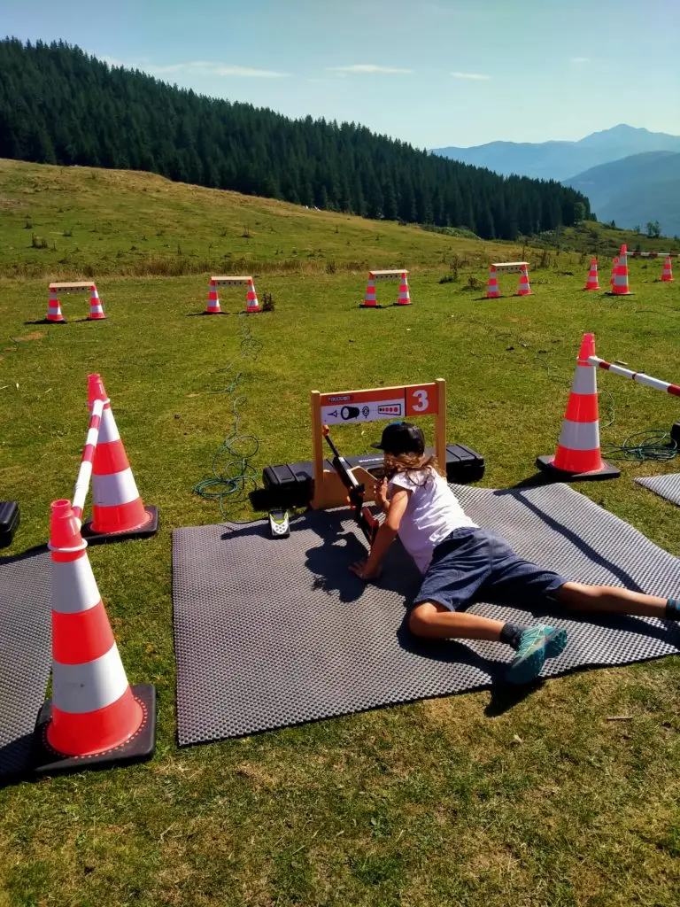 Adolescent couché sur un tapis de biathlon visant la cible avec la carabine optique au col du Soulor