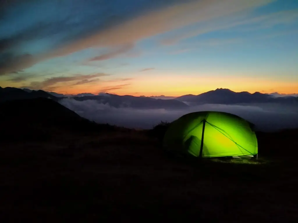 Tente verte éclairée sur le site de bivouac au coucher du soleil dans le Val d'Azun