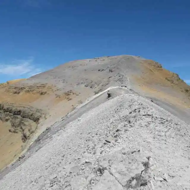 Crête rocheuse en haute montagne dans les Pyrénées, empruntée lors d’une randonnée encadrée par un accompagnateur en montagne sous un ciel bleu dégagé. Marmottes des Pyrénées .
