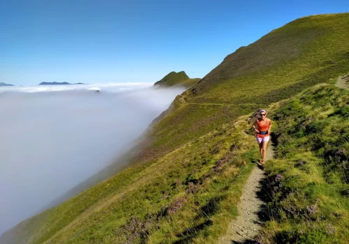 Traileuse courant sur un sentier de montagne avec la mer de nuage à Hautacam