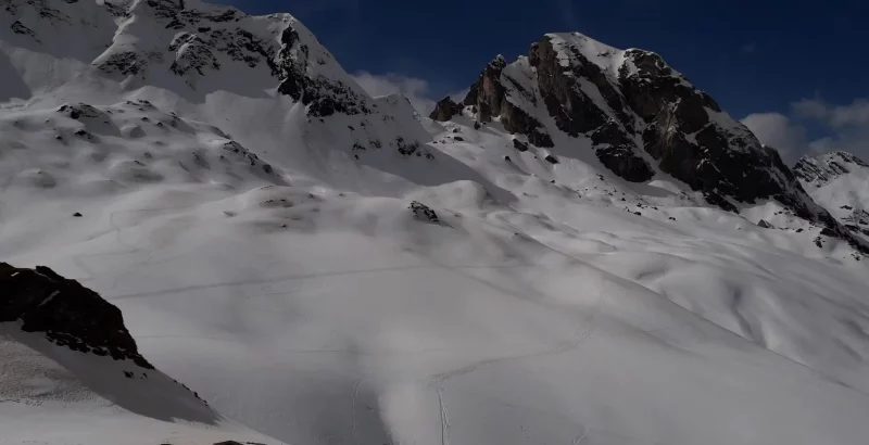 Sommet rocheux enneigé avec un flanc vallonné tout blanc propice à la raquette