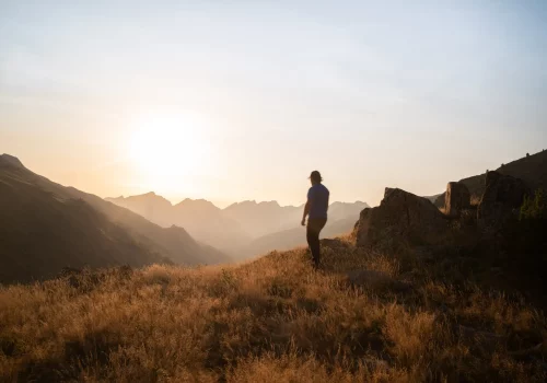 Homme face à la montagne au lever de soleil