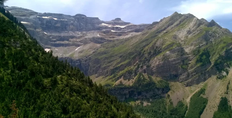 Vue sur la partie ouest du cirque de Gavarnie avec toutes les crêtes frontalières minérales, les estives, les plissures de la roche et la forêt au premier plan