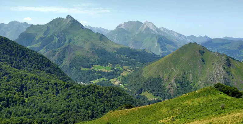 Vue estivale sur le col des Bordères et les Gabizos avec un ciel bleu et une montagne verdoyante d'estives et de forêts