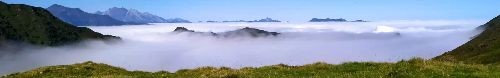 Vue depuis une estive sur une mer de nuage avec un ciel bleu et des sommets à l'horizon