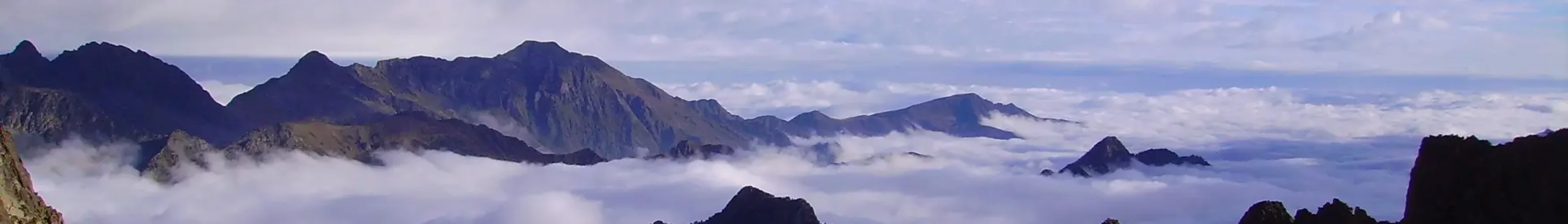 Mer de nuage percée par les sommets minéraux sur un ciel nuageux